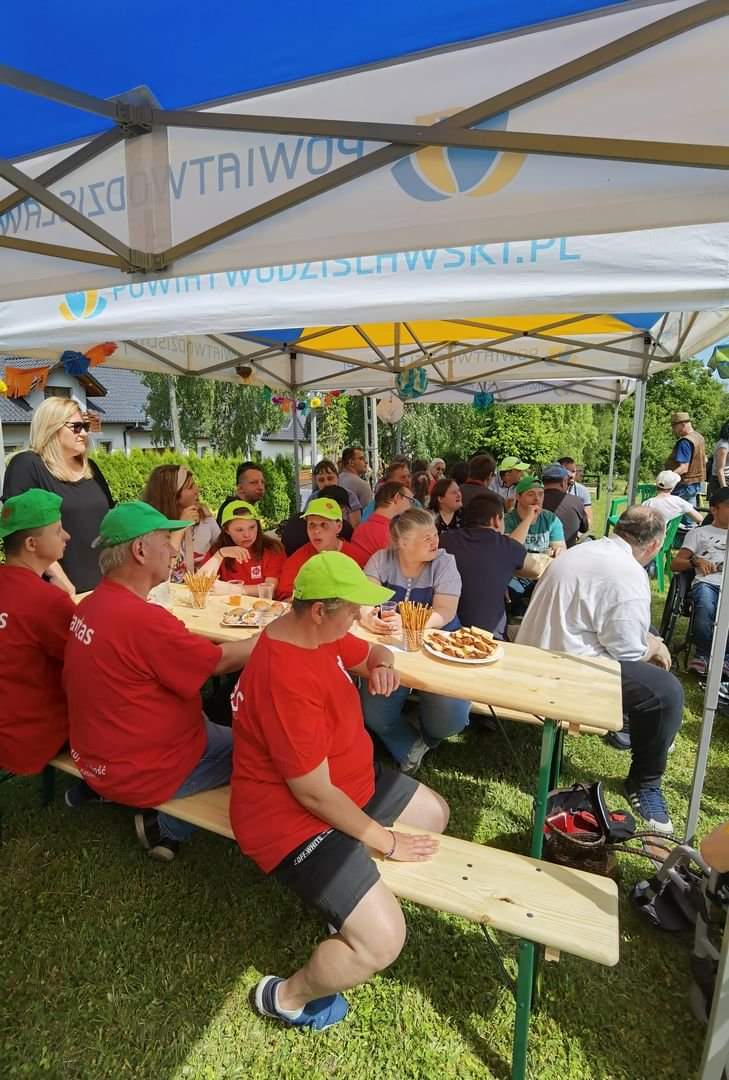 Osoby siedzące przy stołach pod namiotem
