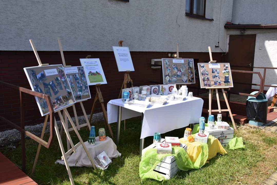 Na zdjęciu widać stół z pracami uczestników oraz sztalugi ze zdjęciami.