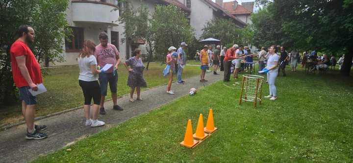 Na zdjęciu widać grupę osób biorących udział w konkurencjach sportowych rzycanie do celu itp