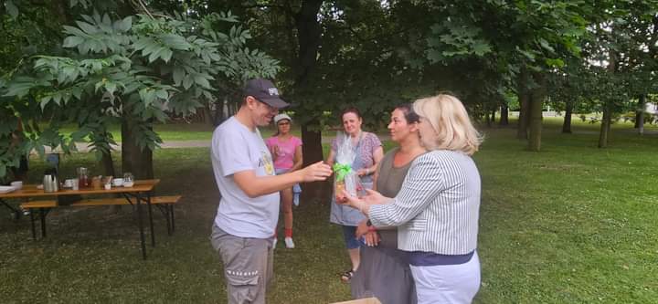 Na zdjęciu widać uczestnika odbierającego nagrodę od Dyrektor DPS-u, w tle ogród.