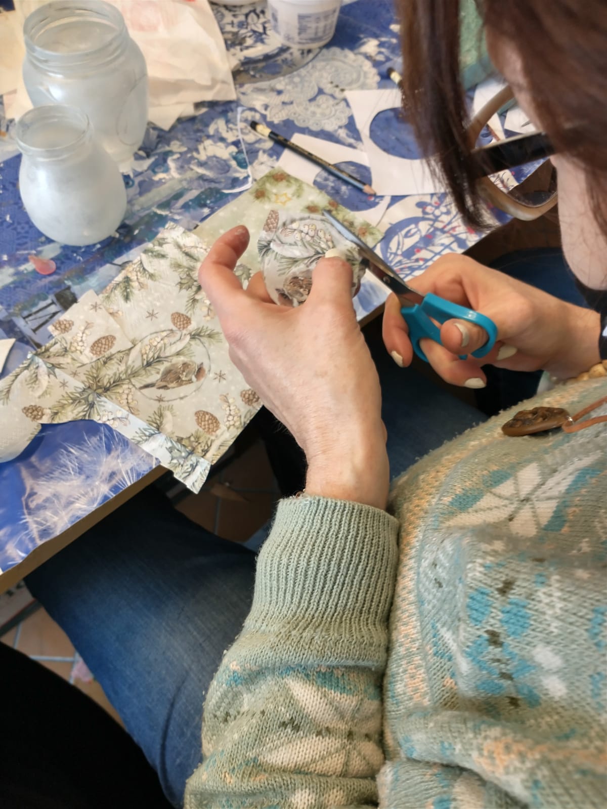Na zdjęciu widać osobę wycinającą motyw dekoracyjny z serwetki do decoupage.