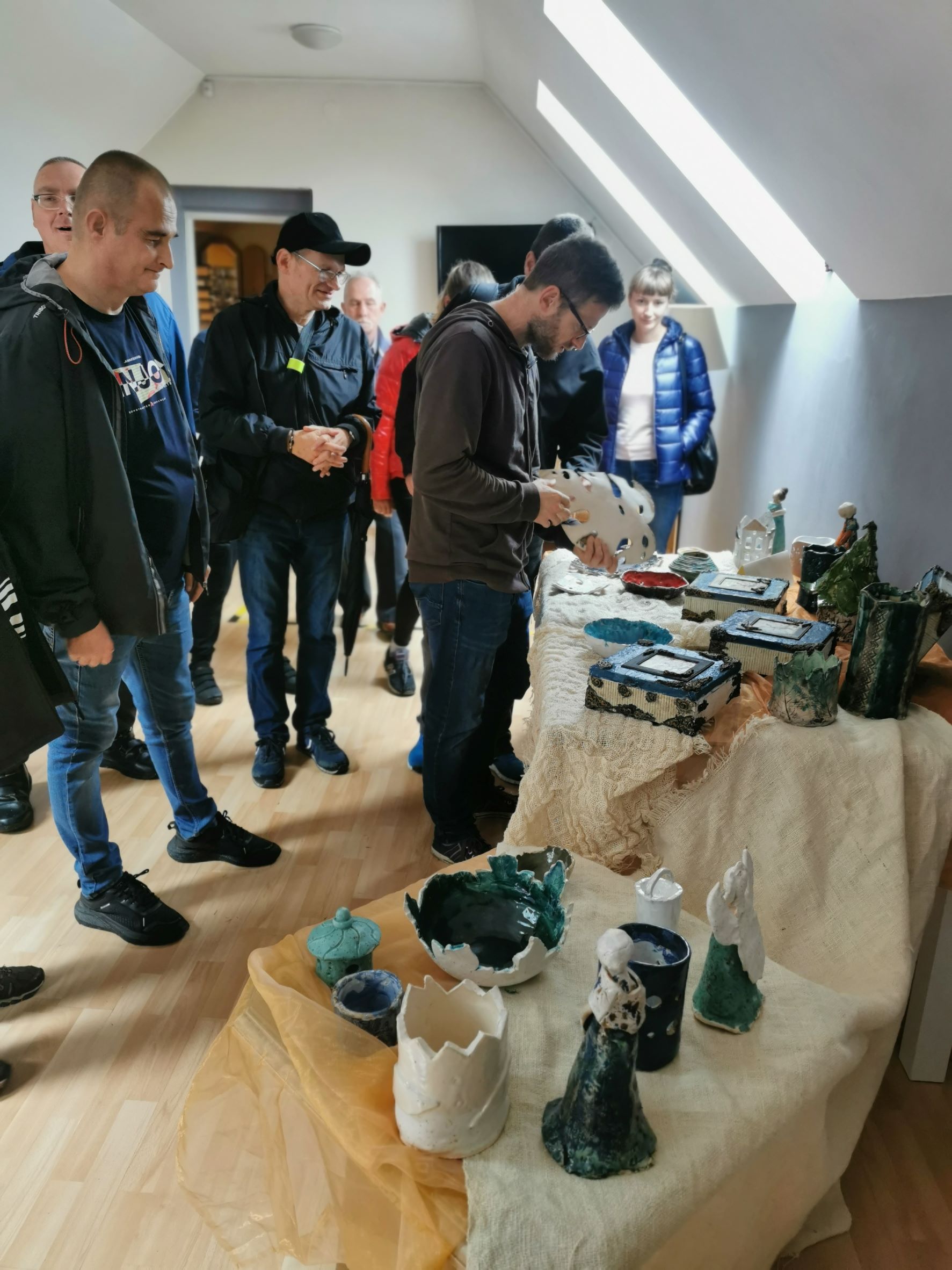 Grupa osób oglądająca wystawę prac uczestników Ośrodka Wsparcia Perła.