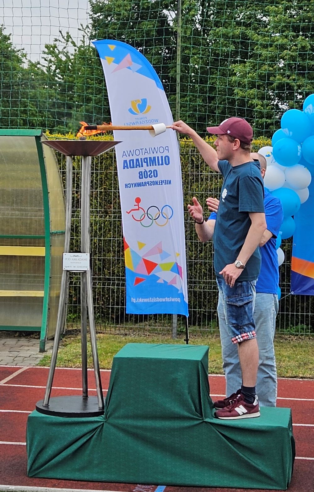 Na zdjęciu widać mężczyznę podpalającego znicz olimpijski za pomocą pochodni.