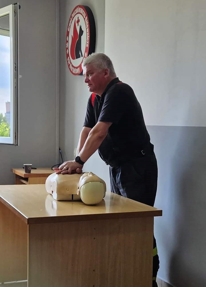 Na zdjęciu widać strażaka prezentującego jak prawdiłowo wykonywać resuscytację.