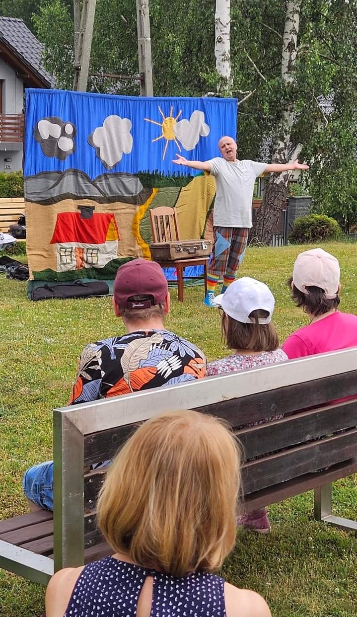 Na zdjęciu widać ludzi siedzących tyłemdo oglądających przedstawienie teatralne w plenerze.